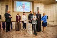 Chłopiec otrzymuje nagrodę, w tle dorośli