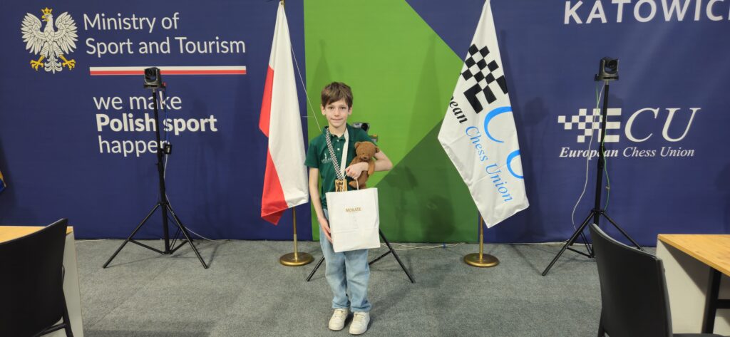 Uczeń stoi z nagrodami za turniej szachowy