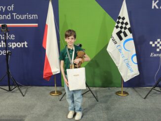 Uczeń stoi z nagrodami za turniej szachowy