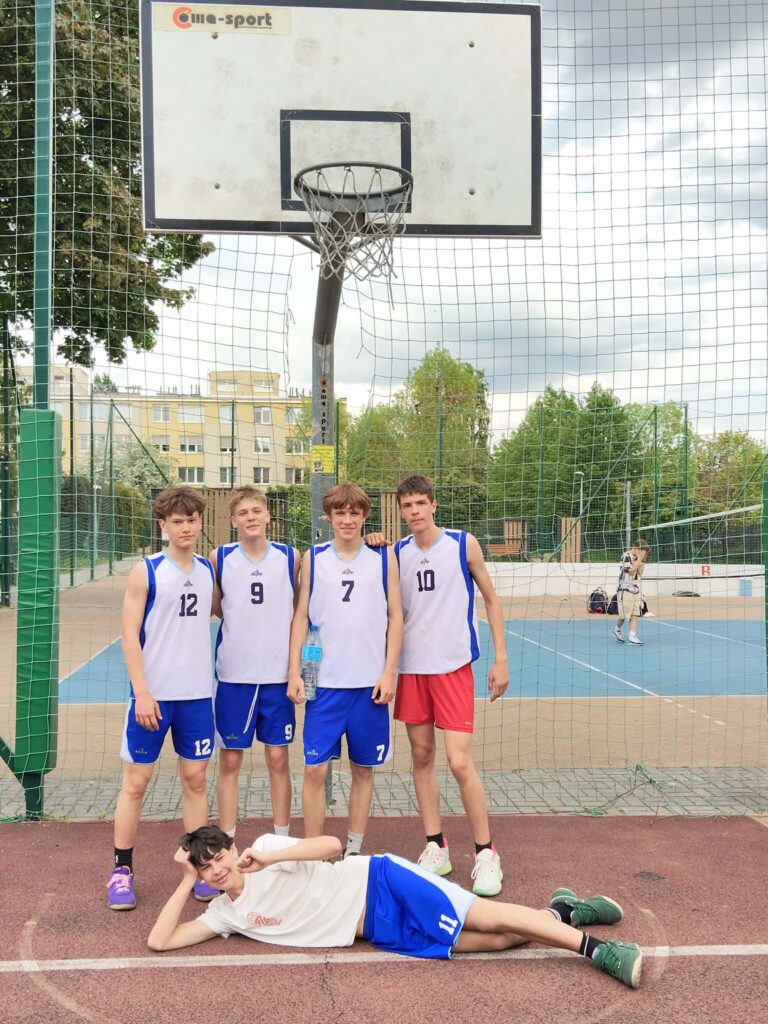 pięciu chłopców w strojach sportowych ba boisku do koszykówki